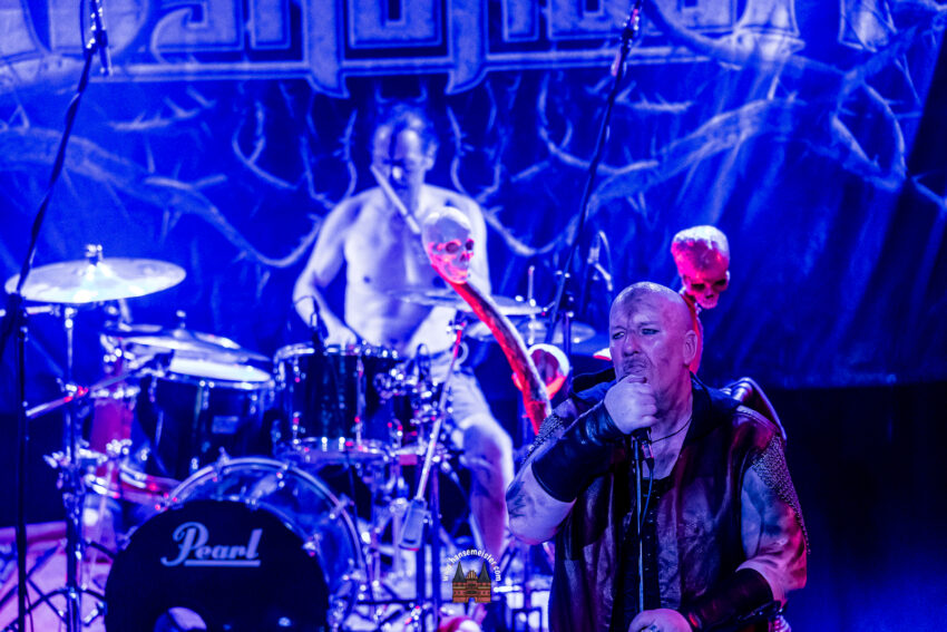 im Vordergrund ist der Sänger Charon der Fährmann: zu sehen, im Hintergrund etwas verschwommen der Schlagzeuger Hammerdal, der seit 2021 die Band Ragnaröek begleitet