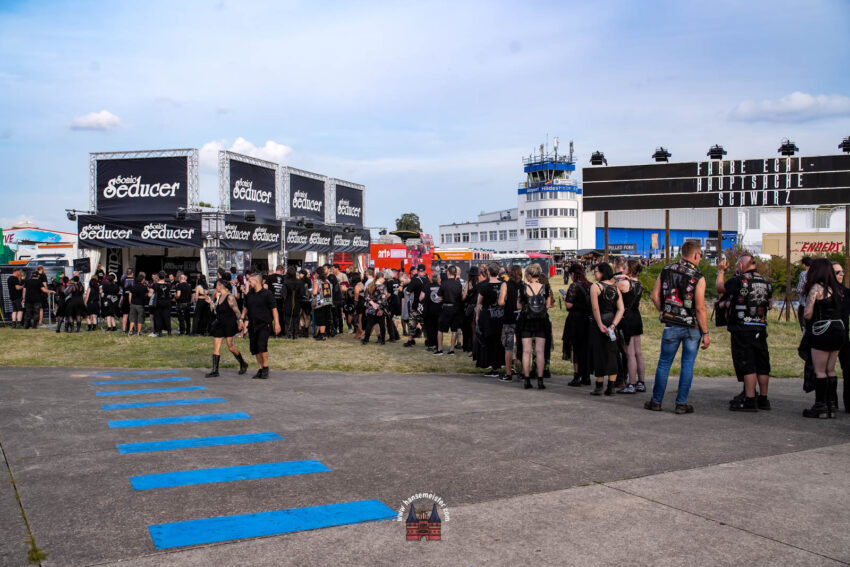Dieses Bild zeigt den Stand des Musikmagazins Sonic Seducer auf dem M'era Luna Festival in Hildesheim.Das M'era Luna ist eines der größten Festivals der Schwarzen Szene in Deutschland und findet auf dem Flugplatz Drispenstedt statt.Im Hintergrund ist der charakteristische Kontrollturm des Flughafens zu sehen.