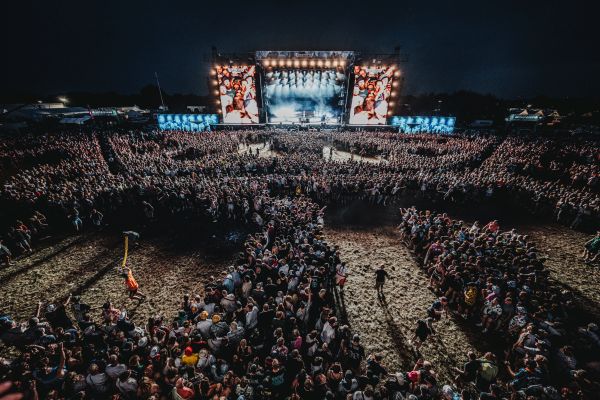 Vogelperspektive auf eine riesige Menschenmenge vor der beleuchteten Hauptbühne des Deichbrand Festivals 2025 bei Nacht.
Gänsehaut pur: Tausende Fans feiern gemeinsam vor der Mainstage. Foto:
 FINCH_fotoduda039